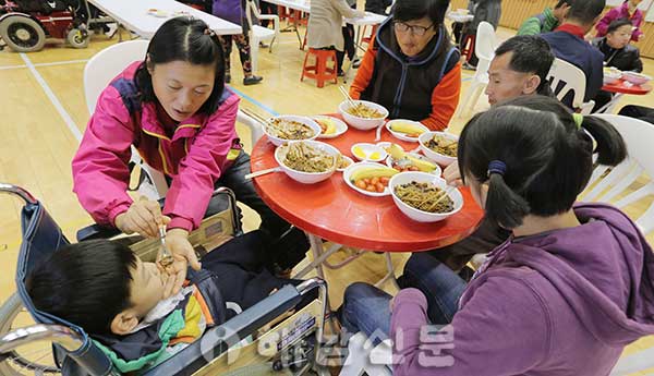 ▲ 한국SNS 연합회 사랑의 짜장차가 대접한 짜장면을 장애인 가족이 맛있게 먹고 있다.