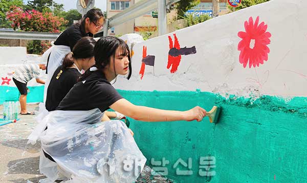 ▲ 벽화 그리기 청소년 자원봉사에 참여한 학생들이 구슬땀을 흘리며 담장에 색을 입히고 있다.