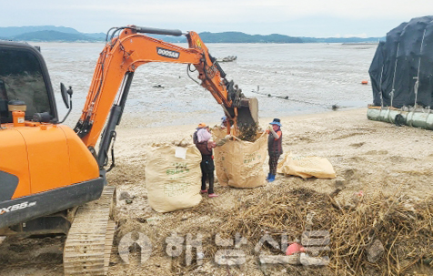 ▲ 집중호우로 해안가에 쌓인 해양쓰레기를 굴삭기를 이용해 톤백에 담고 있다.