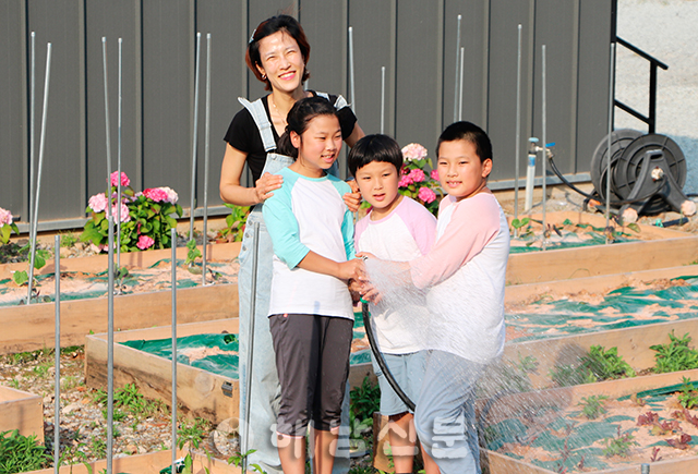 ▲ 어머니 김하나 씨와 3남매가 마을 공동텃밭에 물을 주고 있다.
