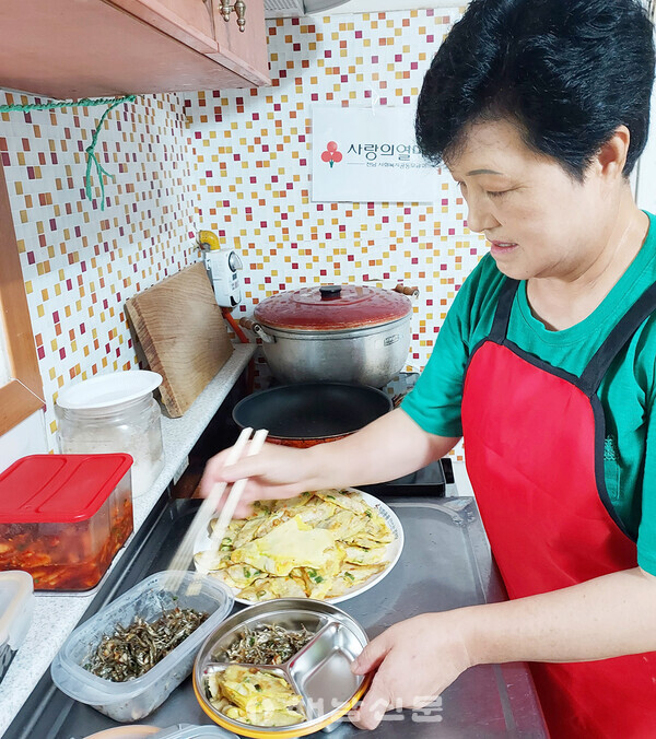 ▲거동이 불편해 마을회관을 찾기 힘든 주민을 위해 배 순이 씨가 반찬을 담고 있는 모습.