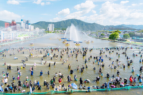 ▲축제 방문객들이 대왕장어 잡기 체험을 즐기고 있다. 뒤편으로는 탐진강 일대에서 수상자전거, 우든보트 등을 즐기고 있다.